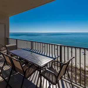 Dine al fresco at the spacious table, enjoying panoramic views and gentle breezes from the inviting beachfront balcony