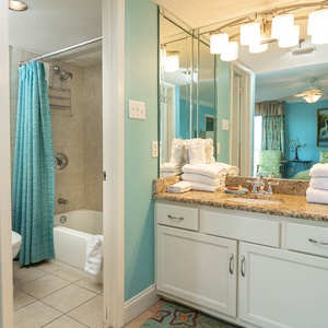 The master bath features a tub/shower combo, vibrant turquoise walls, and a stylish vanity with neatly arranged towels