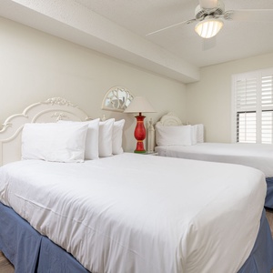 Rest comfortably in this charming guest bedroom with two double beds, a colorful lamp, and natural light