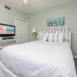 Relax in this comfortable guest bedroom featuring a plush queen bed, TV, and cheerful decor for a restful stay