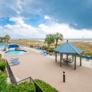 Relax by the poolside, enjoying the inviting lounge chairs and easy access to the beach just beyond the grassy area