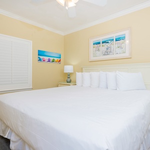 Guest bedroom featuring a large king bed with white linens, complemented by coastal artwork and a charming nightstand