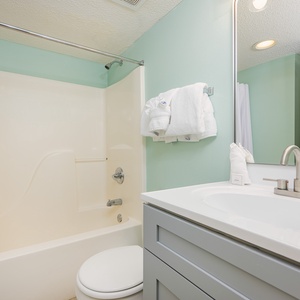 Towels await after refreshing showers in the bathroom with soft mint walls and a tub shower combo