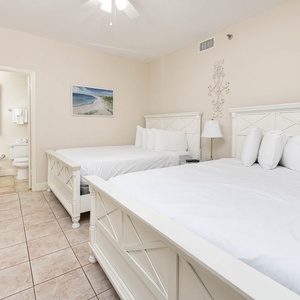 Relax in this guest bedroom featuring two double beds, soft linens, and a beach art for a calming vibe