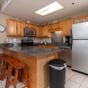 Warm wood cabinetry complements the granite countertops in this inviting kitchen area with a breakfast bar and seating
