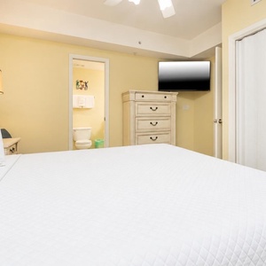 Rest in this inviting bedroom featuring a king bed, a flat-screen TV, and soft yellow tones for a relaxing atmosphere
