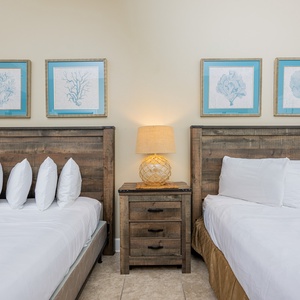 Inviting guest room featuring two comfortable queen beds, coastal art, and a relaxing vibe