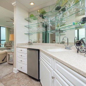 Enjoy a drink at the stylish wet bar area with an ice maker, sleek countertops, and decorative glassware