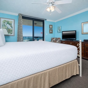 Cozy king bed in the master suite offers a view of the balcony and beach beyond, enhancing relaxation