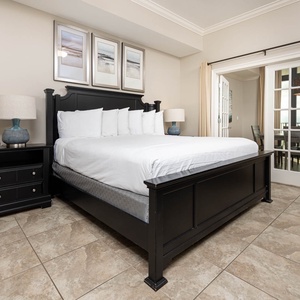 The master bedroom features a plush king bed, elegant decor, and a charming view through glass doors leading to a dining area