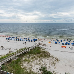 Experience stunning beachfront views with colorful umbrellas and beachgoers from this inviting living area