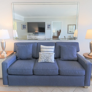 The living area features a comfortable blue sofa, stylish lamps, and a large TV, perfect for relaxation