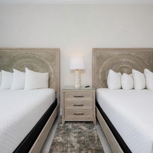 Relax in the guest room featuring two queens with soft linens, fluffy pillows, and soothing design