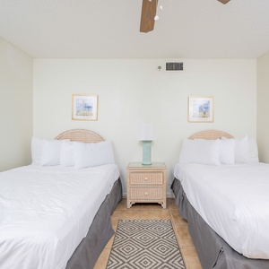 Relax in this guest bedroom featuring two double beds, a stylish lamp, and charming coastal artwork on the walls