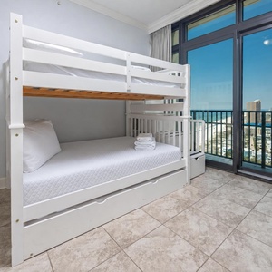 This cozy bedroom features a white full bunk bed with a full trundle, and a stunning beachfront view