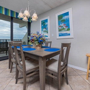 Enjoy meals at this dining area with a beautiful beachfront view, featuring a floral centerpiece and blue placemats
