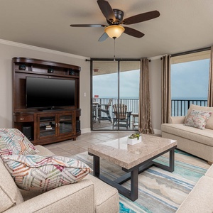 Living room features a cozy sofa with a colorful accent pillow, a stylish coffee table, and sliding doors to a beach balcony