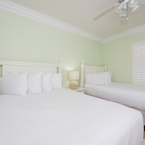Enjoy restful nights in this serene guest room featuring two double beds, soft linens, and calming green walls
