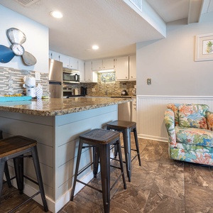 The kitchen features stylish cabinetry, stainless appliances, and a bar stool area perfect for relaxing