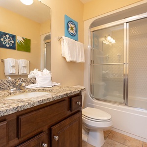 This bathroom features a stylish granite countertop, modern fixtures, and vibrant artwork, creating a refreshing retreat