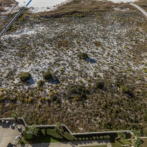 Expansive view of the beach access path leading to the soft white sand, framed by lush greenery and a pool area below