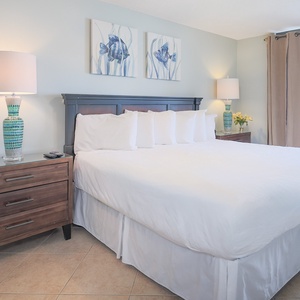 Relax in this serene master bedroom, featuring a king bed, stylish decor, and beachfront balcony access