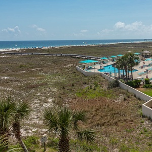 Expansive views of the beach and pool area showcase vibrant umbrellas and lounge chairs set against lush greenery
