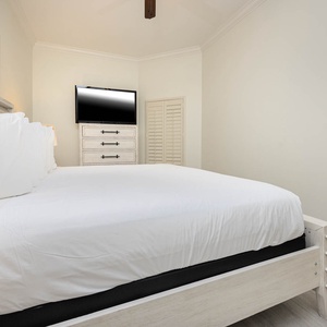 This cozy bedroom features a comfortable bed, a mounted TV, and stylish decor, perfect for a relaxing getaway