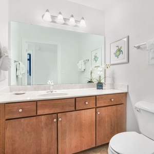 The half bath features a sleek vanity with wood cabinets, a large mirror, and decorative accents for a refreshing retreat