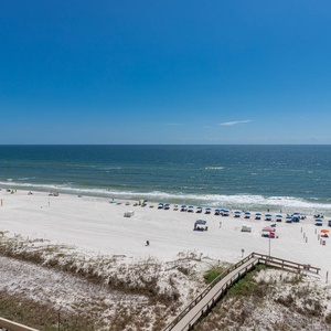 The view showcases a pristine beach with colorful umbrellas and lounge chairs set against a vibrant blue sky and ocean