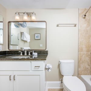This bathroom features a sleek granite countertop, modern fixtures, and a relaxing tub-shower combination for your comfort
