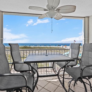 Enjoy breathtaking views from this cozy balcony with stylish seating, perfect for relaxing by the beach