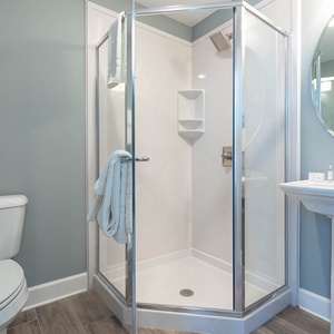 Enjoy a relaxing shower after a day at the beach in this guest bath with stylish accents and fluffy towels