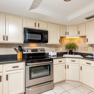 Kitchen featuring black and stainless appliances, granite countertops, and warm wood accents for a cozy atmosphere