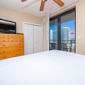Relax in this guest bedroom featuring a comfortable queen bed, a TV, and a view through sliding doors to the outdoors