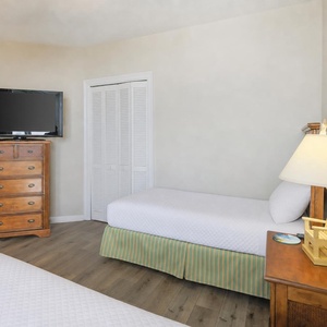 This cozy bedroom features two beds, a TV for entertainment, and warm wood accents, creating a welcoming retreat