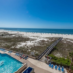 Relax by the poolside, enjoying the view of the beach and clear waters under a bright blue sky