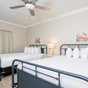 Rest in this inviting guest bedroom featuring two queen beds, soft linens, and cheerful coastal decor