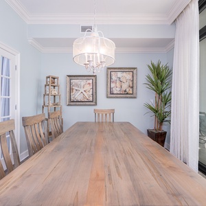 Dining area featuring a large wooden table, stylish decor, and a view through glass balcony doors