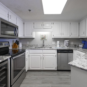 This modern kitchen features white cabinetry, granite countertops, and a breakfast bar, perfect for preparing meals