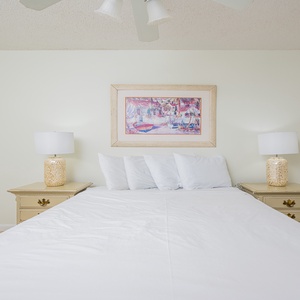 Soothing guest bedroom featuring a large queen bed complemented by decorative lamps and vibrant artwork