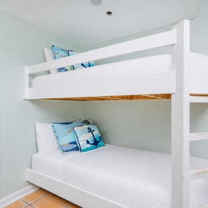 Cozy twin bunk beds with nautical-themed pillows create a fun and inviting space for kids in this charming living space