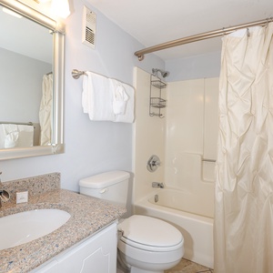 The bathroom features a stylish countertop, a spacious shower, and fresh towels for a refreshing experience