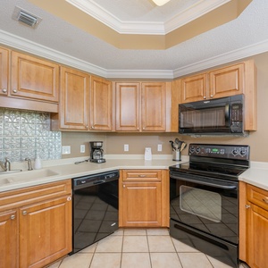 Prepare meals in this kitchen with wooden cabinetry, black appliances, and stylish backsplash