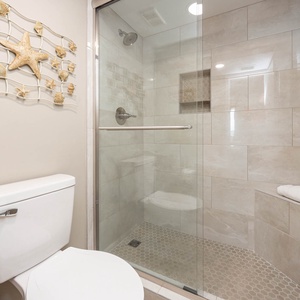Master bath featuring a walk-in shower with glass doors, a modern toilet, and decorative shell-themed wall art