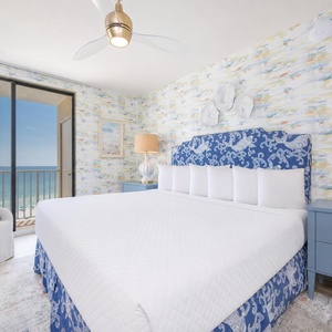Welcoming master bedroom featuring a plush king bed, stylish blue accents, and a stunning view from the balcony