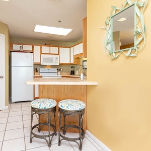 Bright kitchen area featuring a breakfast bar with stylish stools, ample cabinetry, and white appliances
