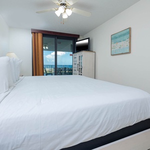 Master suite featuring a king bed, a TV, and the extended balcony with views of the beach, enhancing the vacation experience