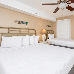 Plush pillows invite you to sink into white linens in this guest suite with twin and queen beds nearby
