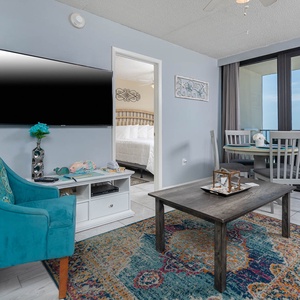 This inviting condo features a vibrant chair, a flat-screen TV, and stunning beachfront views through large windows